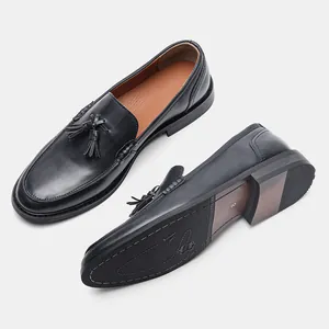 Detail view of men's black leather tassel loafers showing top and outsole
