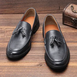 Detail view of classic black leather tassel loafers for men on a vintage wooden background
