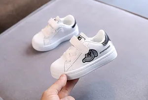 Detail view of white shell-toe sneakers for kids with cartoon embroidery