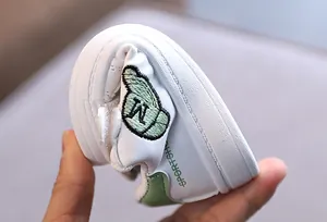 Close-up view of the highly flexible soft sole on children's white and green casual shoes