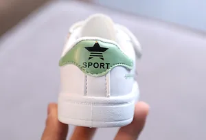 Close-up of a white toddler sneaker showing the green heel patch and star logo
