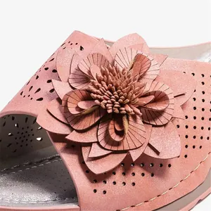 Dettaglio macro di ornamento floreale in PU rosa e design traforato su ciabatte con zeppa