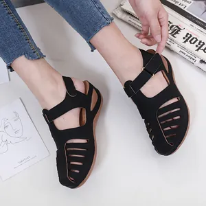 Nahaufnahme von schwarzen Keilsandalen mit Ausschnitten, getragen in einem Lifestyle-Set