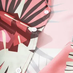 Primer plano detallado de una camisa hawaiana con estampado de hojas tropicales y botones