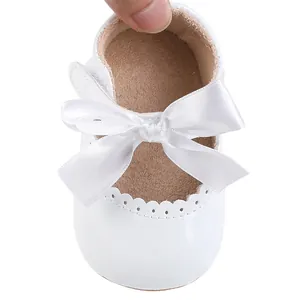 Detailansicht eleganter weißer Baby-Prinzessin-Schuhe mit schöner Satinschleife.