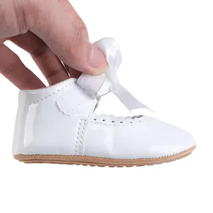 Detailansicht weißer Babyschuh aus Lackleder mit Schleife und praktischem Klettverschluss