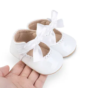 Detailansicht der weißen Lackleder-Babyschuhe mit eleganter Seidenschleife für Mädchen