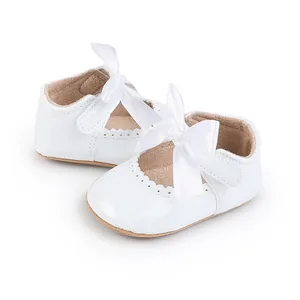 Detailansicht weißer Baby-Prinzessinenschuhe aus Lackleder mit Satinschleife und Borte