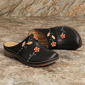 Close-up of black leather clogs for women with colorful floral embroidery and stitching