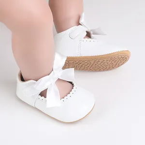 Detailansicht der weißen Baby-Prinzessin-Schuhe mit Satinschleife und Lackoberfläche.