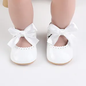 Detailansicht weißer Baby-Prinzessin-Schuhe mit großen Satinschleifen und Wellenrand