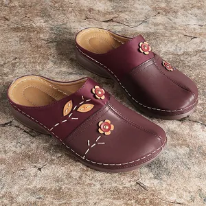 Close-up of burgundy women's flat mules with floral appliques and contrast stitching
