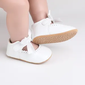 Nahaufnahme weißer Prinzessinnenschuhe für Babys mit Schleife und rutschfester Sohle
