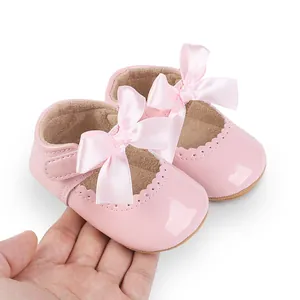 Nahaufnahme von rosa Lackleder-Babyschuhen mit dekorativen Schleifen für Mädchen
