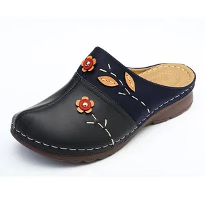 Detailed view of floral applique and contrast stitching on navy and black mules