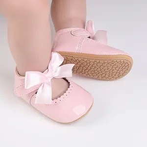 Detailansicht von rosa Baby-Lackschuhen mit Satinschleifen und rutschfesten Sohlen