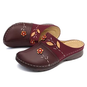 Detailed close-up view of women's maroon leather clogs featuring floral appliques and contrast stitching