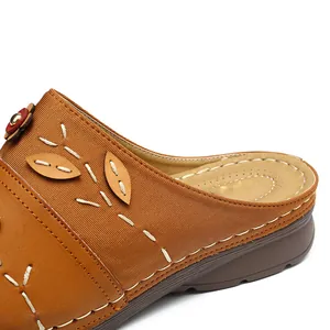 Close-up of brown women's closed-toe sandal with decorative flower and stitching