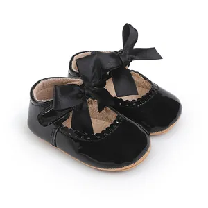Makroaufnahme von schwarzen Lackleder-Prinzessinenschuhen für Babys mit Zierschleifen.