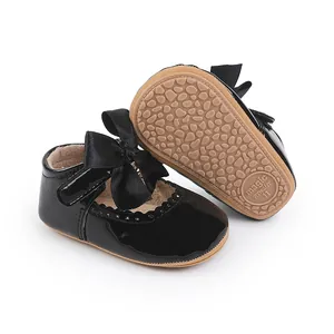 Detail von schwarzen Baby-Lackschuhen mit großer Satinschleife und rutschfester Sohle