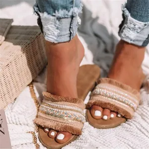 Detailansicht der flachen Boho-Sandalen mit Fransen und Perlenstickerei am Modell