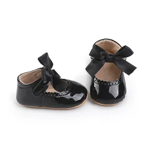Detailansicht glänzender schwarzer Baby-Mädchen-Schuhe mit eleganter Schleifendekoration.