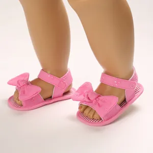 Détail de sandales roses pour bébé avec grands nœuds et fermeture velcro pour l'été