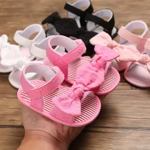 Vue détaillée de sandales roses pour bébé avec un grand nœud et une semelle souple