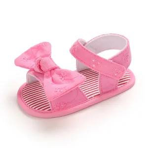 Dettaglio di sandali rosa per neonata con ricami floreali e fiocco grande