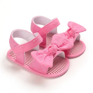 Dettaglio di sandali rosa per neonata con fiocco decorativo e ricamo floreale