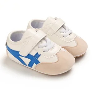 Close-up detail of white baby walking shoes featuring soft soles and blue stripe design