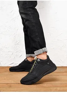 Detailed view of men's black leather casual shoes shown on a rustic wooden floor texture
