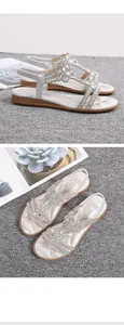 Close-up of silver rhinestone sandals with flower hollow design on gray carpet.