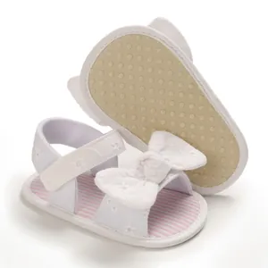 Dettaglio dei sandali estivi bianchi per bambina con strisce rosa e suola morbida antiscivolo