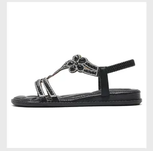 Detail view of black Bohemian flat sandals with sparkling rhinestone flower decor.
