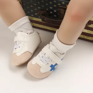 Close-up of cream and beige soft-sole baby walking shoes featuring iconic blue stripes