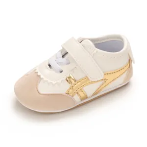 Detailed side view of white and gold baby sneaker with soft sole and velcro strap