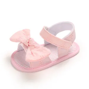 Primo piano di sandali rosa per neonata con fiocco ricamato e suola morbida per primi passi