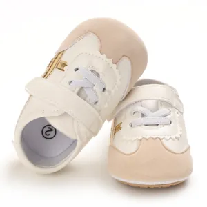 Close-up of beige and white soft-sole baby pre-walker shoes with velcro strap detail.