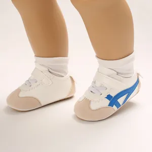 Close-up of white baby pre-walker shoes featuring blue side stripes and velcro