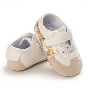 Close-up of baby white sneakers with gold stripes and soft beige suede toe
