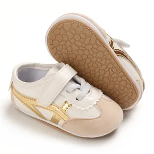 Close-up of white infant walking shoes with soft soles and gold stripes