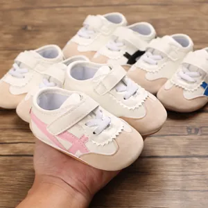 Detail view of infant soft-sole walking shoes showing pink stripe design and suede toe