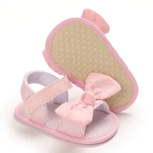 Dettaglio di sandali rosa per neonati con suola morbida antiscivolo e fiocco decorativo.
