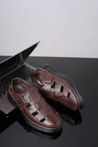 Primer plano de sandalias de cuero marrón para hombre con cierre de velcro