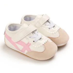 Detail view of baby walking shoes with pink crossed stripes and soft soles