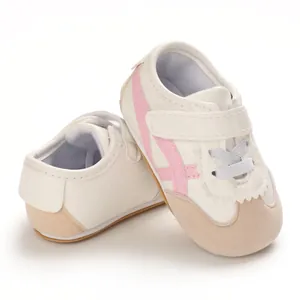 Close-up of white soft sole baby walking shoes with pink stripes and velcro straps