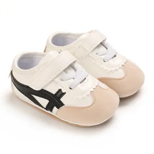 Detailed view of stylish white baby walking shoes featuring black stripes and soft soles