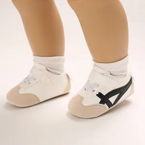 Close-up of white baby walker shoes with black stripes and soft soles for infants