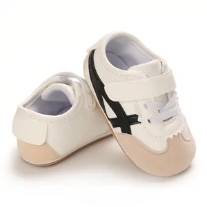 Close-up detail of white baby sneakers with black stripes and soft walking soles